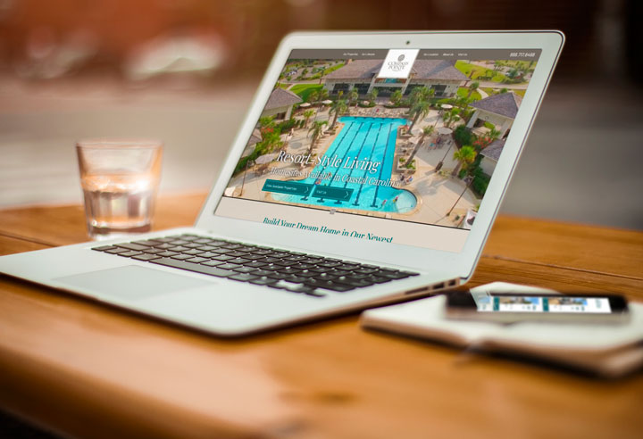 Laptop displaying a custom home builder website featuring a resort-style community homepage design