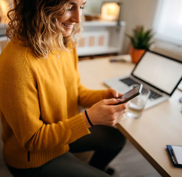 Potential home buyer reading a marketing email from a home builder on her smartphone at home.